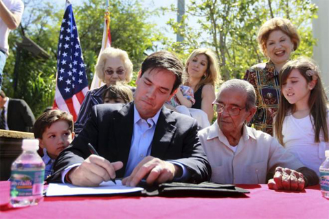 Marco Rubio firma documentos sentado junto a su hijo Anthony (izquierda), su padre Marco (derecha) y su hija Amanda. Foto Joe Raedle