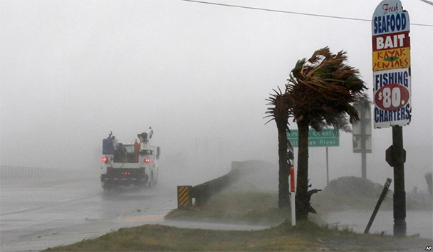 Un camión de trabajo avanza por la Autopista 24 (Hwy 24) mientras el viento del huracán Florence dobla las palmas en Swansboro, Carolina del Norte, el jueves 13 de septiembre de 2018. (AP/Tom Copeland).